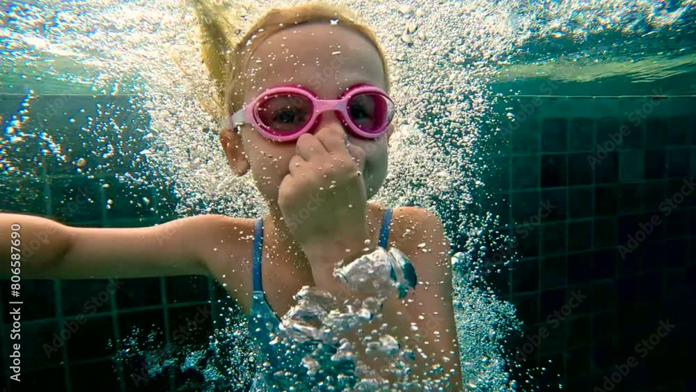 Girl swimming underwater in the pool. Cute little girl with goggles ...