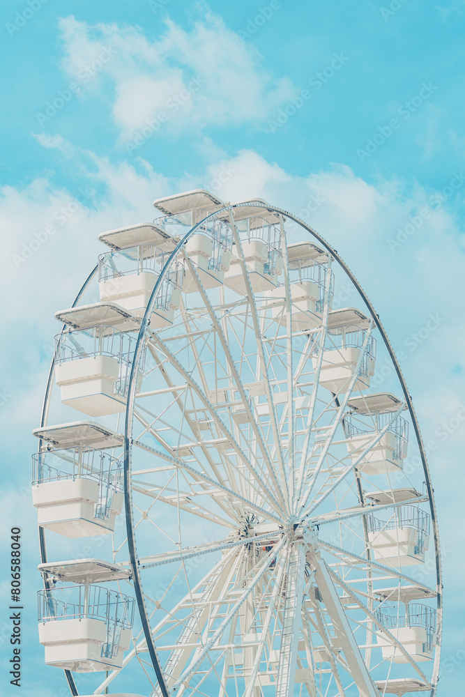 Ferris wheel for panoramic view in amusement park is popular entertaining ride, shot against summer sky on bright sunny day Ferris wheel for panoramic view in amusement park is popular entertaining ride, shot against summer sky on bright sunny day
