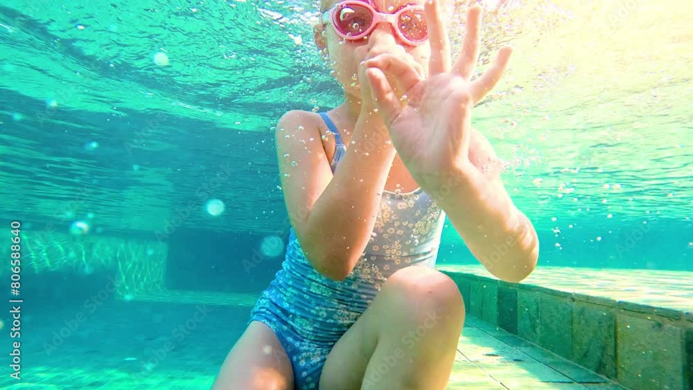 Girl swimming underwater in the pool. Cute little girl with goggles ...