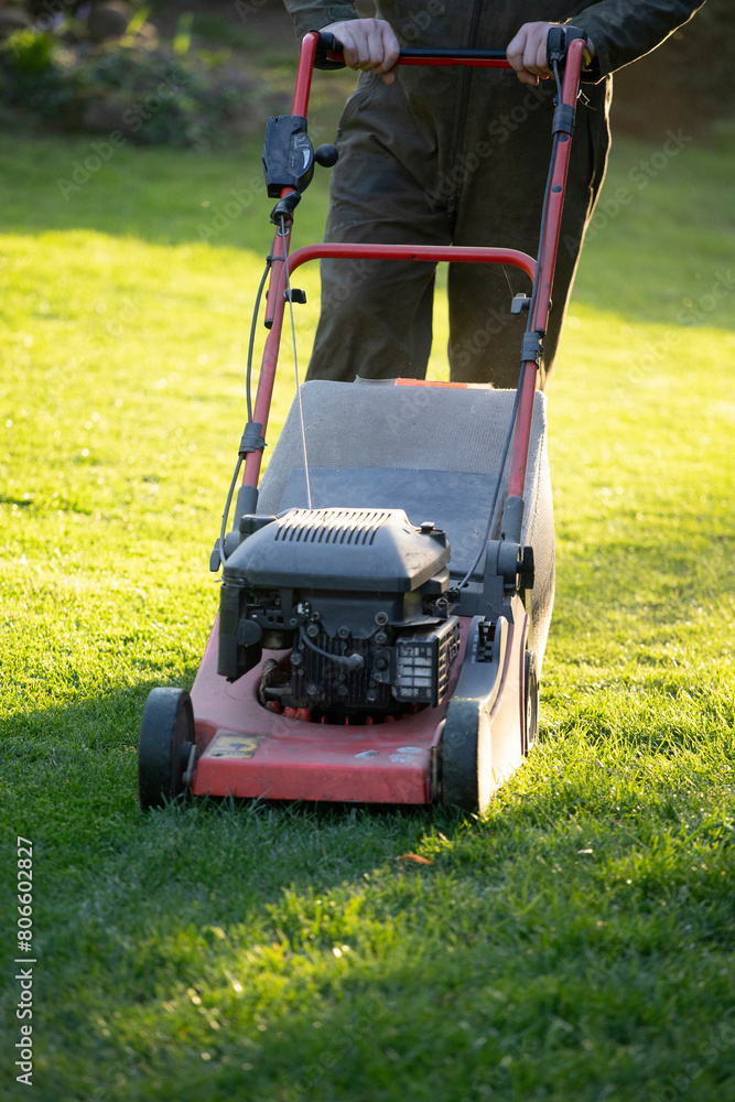 Fototapeta premium Garden worker with lawn mover. Garden works in spring.