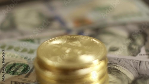 Pile of golden bitcoin coins rotating above 100 US dollar paper bills close up shot photo