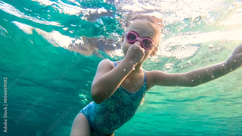 Girl swimming underwater in the pool. Cute little girl with goggles ...