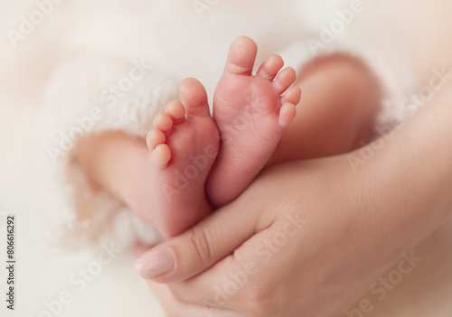 Baby Feet in Mother Hands. Newborn Toes Close up over White Soft background. Mum holding Tiny Feet with Love. Maternity and Childcare Concept