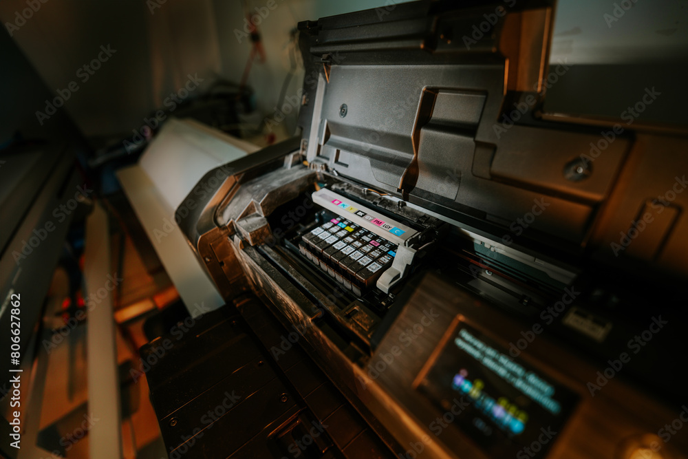 Professional inkjet printer. Ink cartridges. Printing studio. Dark background.