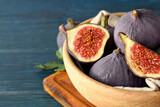 Fresh ripe figs in a wooden bowl on a blue background