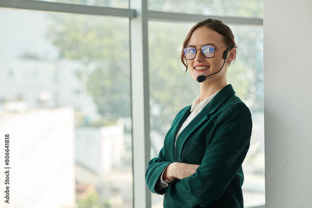 Portrait of smiling confident businesswoman wearing handsfree headset when calling coworker
