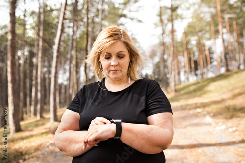 Obraz na plátně Overweight woman preparing for run in nature