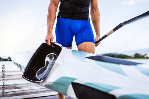 Young canoeist carry canoe and paddle, going on water. Concept of canoeing as dynamic and adventurous sport. photo
