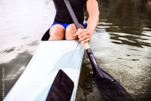 Close up of canoeist sitting in canoe holding paddle, in water. Concept of canoeing as dynamic and adventurous sport. photo