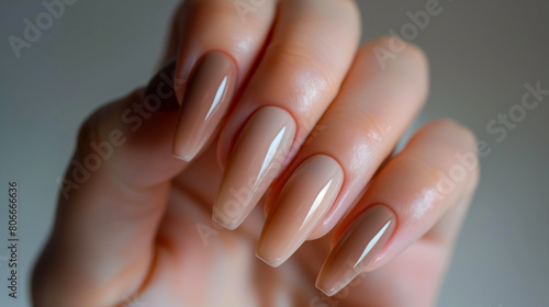 Elegant Nude Color Long Coffin Nails. Close-up of a hand displaying elegant long coffin nails painted in a glossy nude color  showcasing modern nail art.