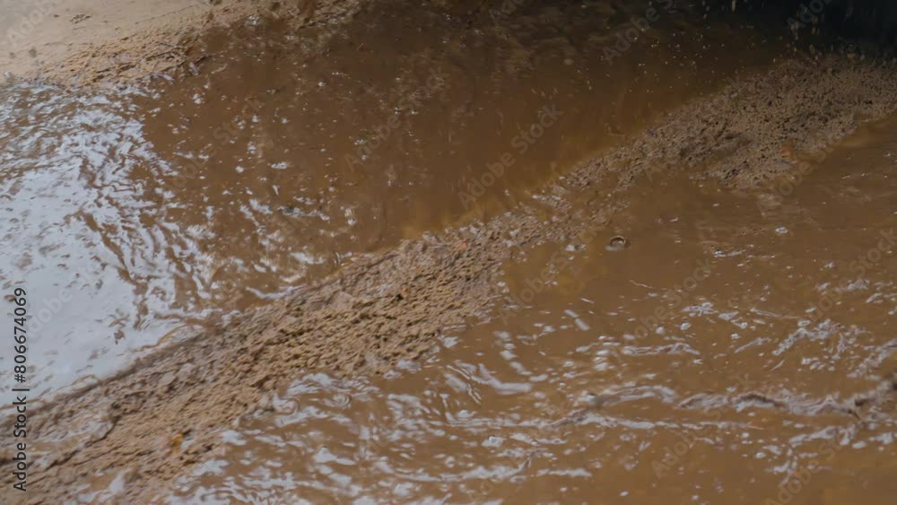 Car drives through puddle, splashing water and mud in different directions. Spinning SUV tires close-up. Rotating tyre on dirty road. Automobile offroad Car drives through puddle, splashing water and mud in different directions. Spinning SUV tires close-up. Rotating tyre on dirty road. Automobile offroad