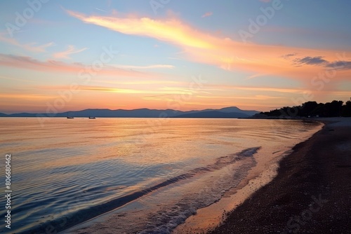 Sunset over calm sea with sandy shore