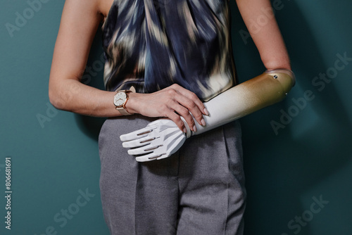Young woman with bionic arm standing in front of on green wall photo