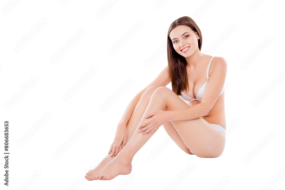 Portrait of slim thin woman sitting over white background in bra and bikini enjoying touching plain legs after depilation Portrait of slim thin woman sitting over white background in bra and bikini enjoying touching plain legs after depilation