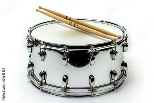 A close-up view of a snare drum with a pair of wooden drumsticks resting on top, isolated on a white background photo