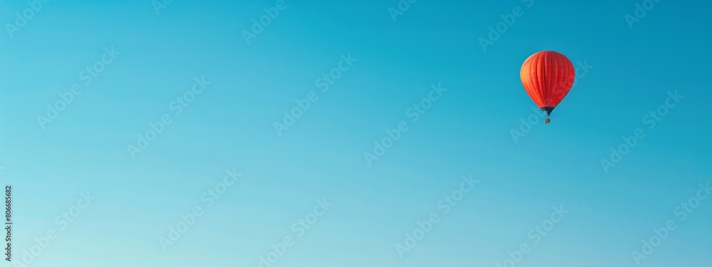 Fototapeta premium A clear blue sky with a single hot air balloon floating peacefully.