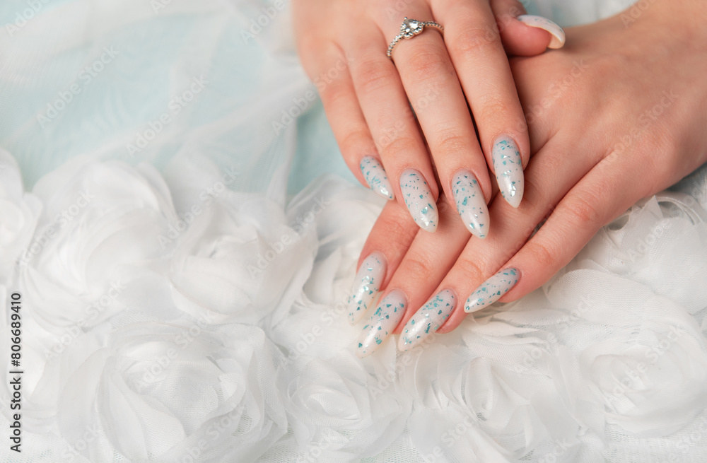 Female hands with blue nail design on blue silk background. Female hands with blue nail design on blue silk background.