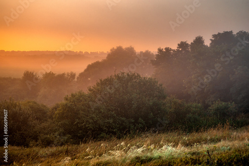 Red sunrise over the beautiful field and trees . Red clouds and sky with sun. Sun over the trees . Summer field at morning . Fog and sky . Beautiful landscape at summer with fog 