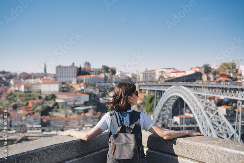 Young tourist enjoying beautiful landscape view in the old town with river and famous iron bridge during sunset in Porto city, Portugal. © Fotografia Juan Reig