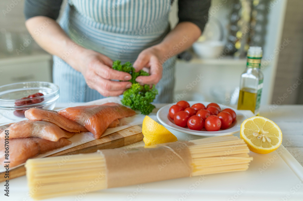 Woman with apron in the kitchen with healthy ingredients on a cutting board for cooking a meal