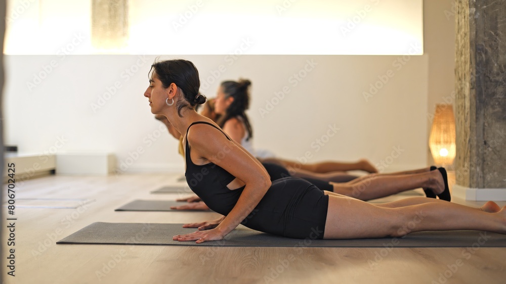 Diverse group practicing cobra pose in a tranquil yoga studio. Diverse group practicing cobra pose in a tranquil yoga studio.