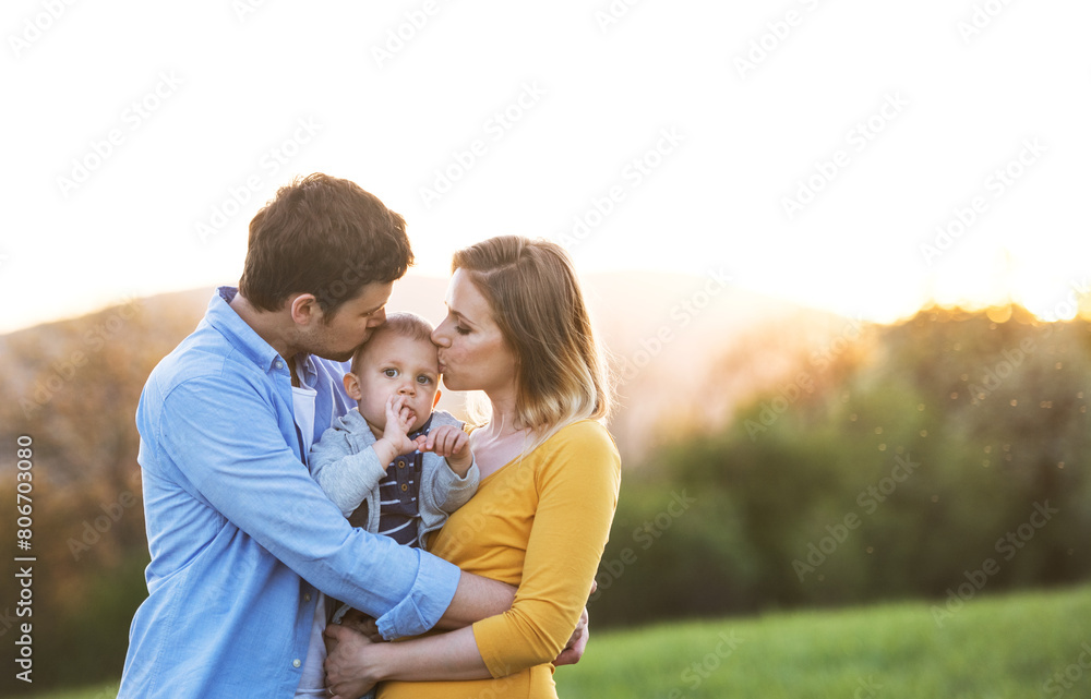 New parents holding small toddler, baby, outdoors in spring nature. Happy family moment New parents holding small toddler, baby, outdoors in spring nature. Happy family moment