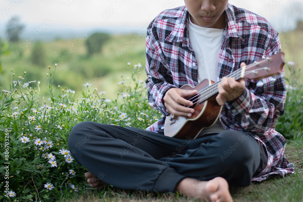 Obraz premium Asian preteen boy playing ukulele and acoustic guitar at home, lifestyle and hobby of children concept.