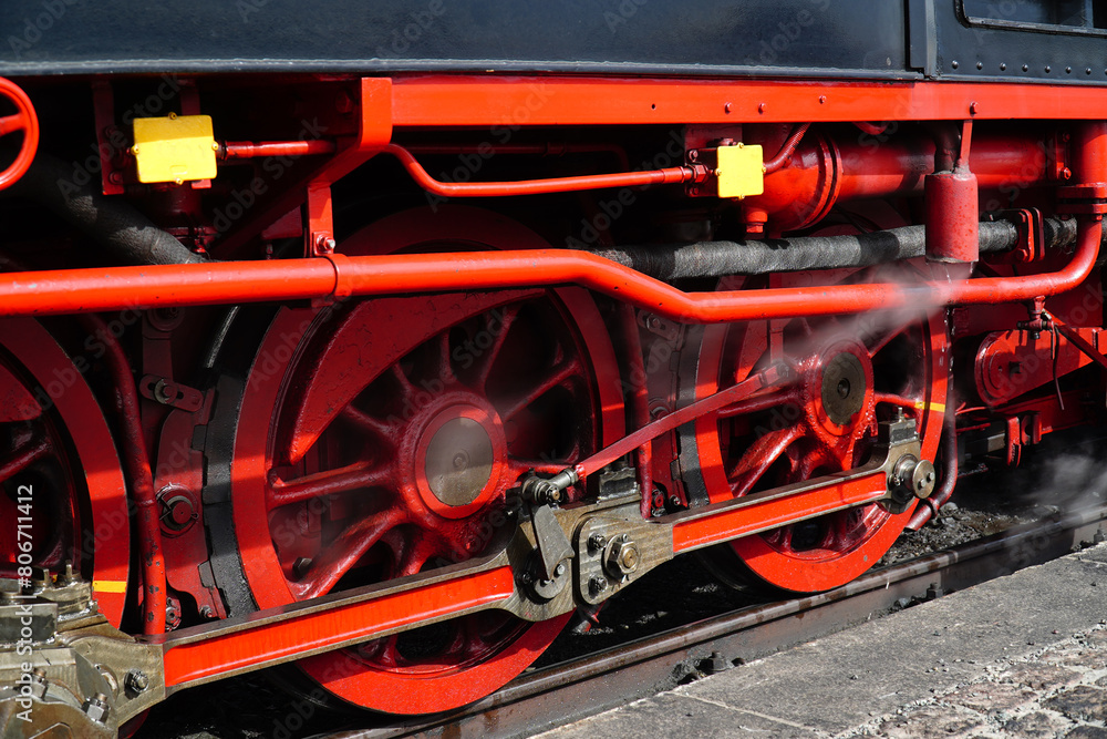 Black and red iron wheels with drive rods of the traditional steam train on the narrow-gauge railroad to Mount Brocken in the Harz Mountains National Park. Wernigerode, Saxony-Anhalt, Germany.