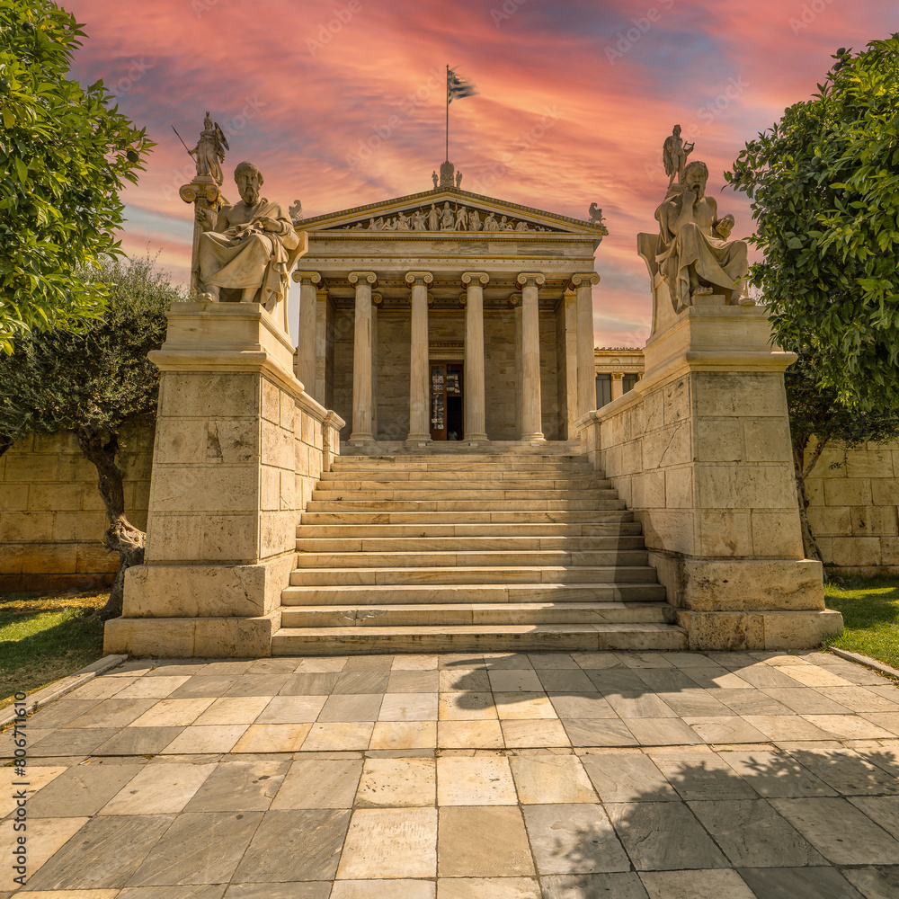 Plato and Socrates statues, the Greek philosophers on both sides of the stairs leading to the national university of Athens under a fiery sky. Romantic travel in Greece.