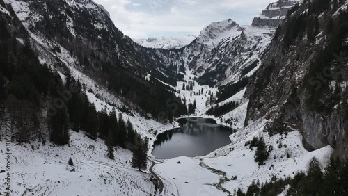 Aerial view of Tahlalpsee in Filzbach, Glarus Nord, Switzerland, cradled by snow-covered mountains and alpine forests photo