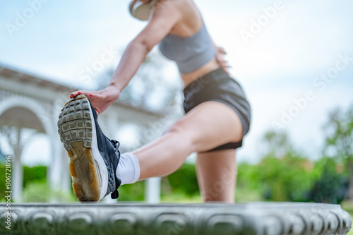 fit, fitness, sport, endurance, race, run, runner, wellness, stretch, jogging. A woman is stretching her leg while wearing a black and white outfit. as the woman works on her flexibility. © Day Of Victory Stu.
