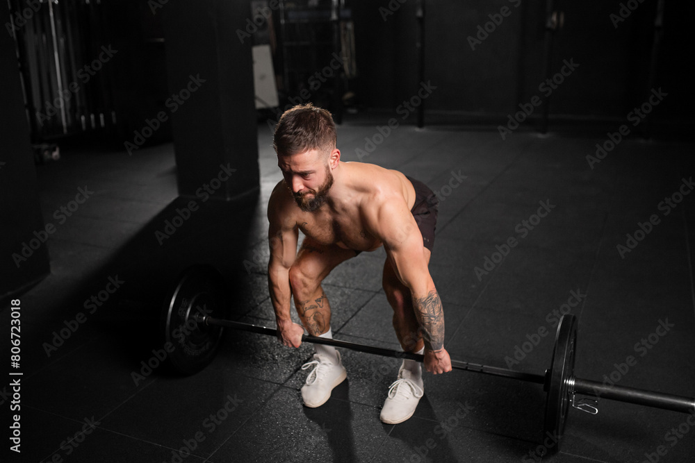 Strong man performing deadlift, lifting barbell from ground. Strength exercise. Routine workout for physical and mental health. Strong man performing deadlift, lifting barbell from ground. Strength exercise. Routine workout for physical and mental health.