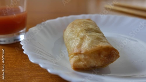 Chinese spring rolls with red sweet and sour sauce, Chinese chopsticks. Asian Chinese cuisine. background with brown table.