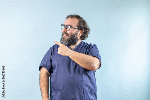 Horizontal banner of smiling young male doctor showing and presenting something with hand, isolated on blue background with copy space on left