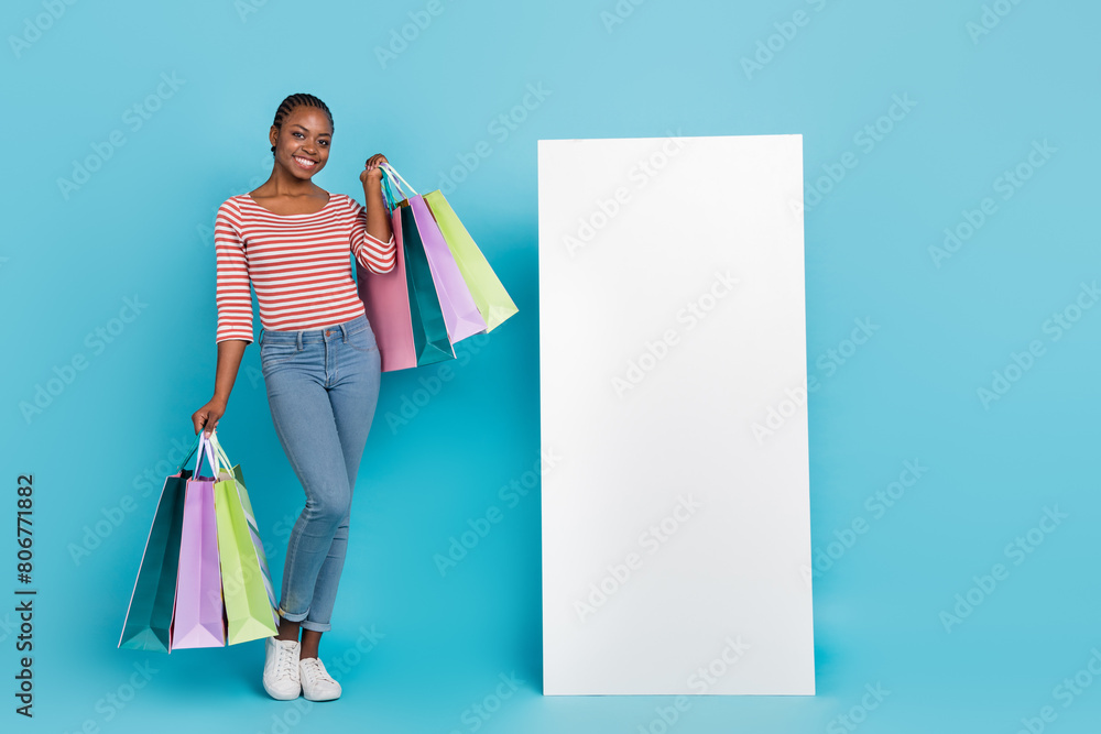 Full length photo of pretty positive person hold packages empty space huge phone screen isolated on blue color background Full length photo of pretty positive person hold packages empty space huge phone screen isolated on blue color background