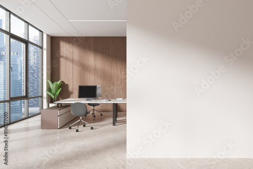 A modern office interior with a wooden wall, city view window, computer on desk, and empty white wall space for a mock-up. Light is natural. 3D Rendering