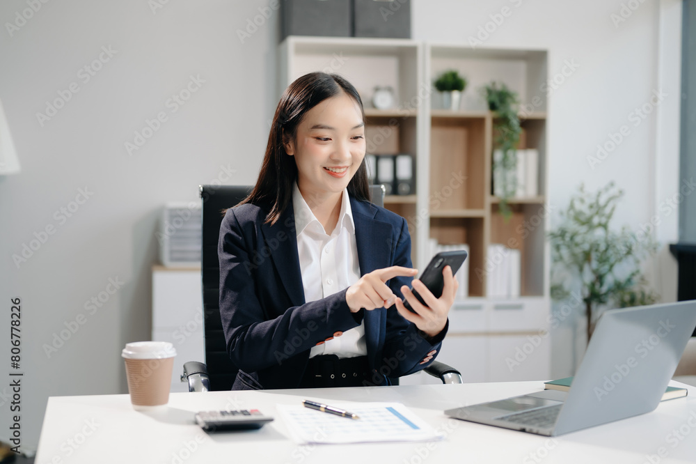Asian woman using laptop and tablet while sitting at her working place. Concentrated at work. Asian woman using laptop and tablet while sitting at her working place. Concentrated at work.