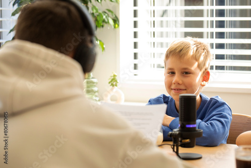 Young boy happily participates in a podcast interview  with microphone. Blogging and podcasting.