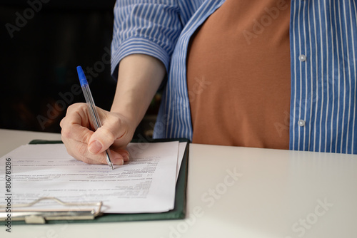 Pregnant woman signing a contract for prenatal care at a gynecology clinic, health insurance coverage, maternity services