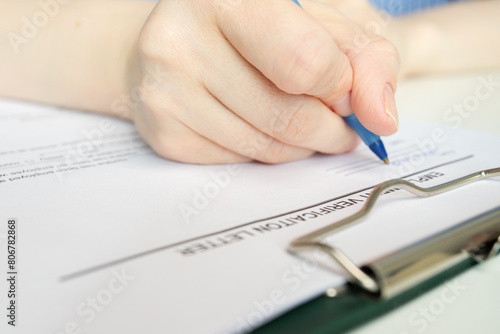 Employment verification letter, hand fills out a document, desk paperwork, corporate meeting.