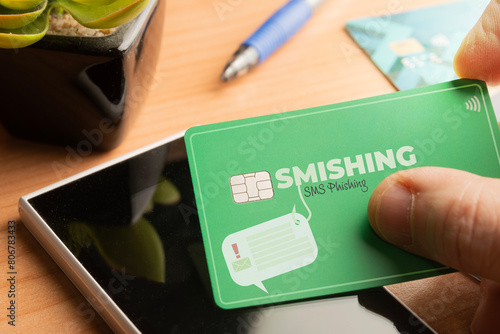 Smishing (SMS message phishing) concept: man hold a credit card over a smartphone