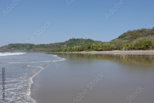 Sandstrand am flachen Meer mit tropischem Wald und Kokospalmen in Costa Rica an der Küste von Montezuma auf der Halbinsel Nicoya bei Puntaremas photo