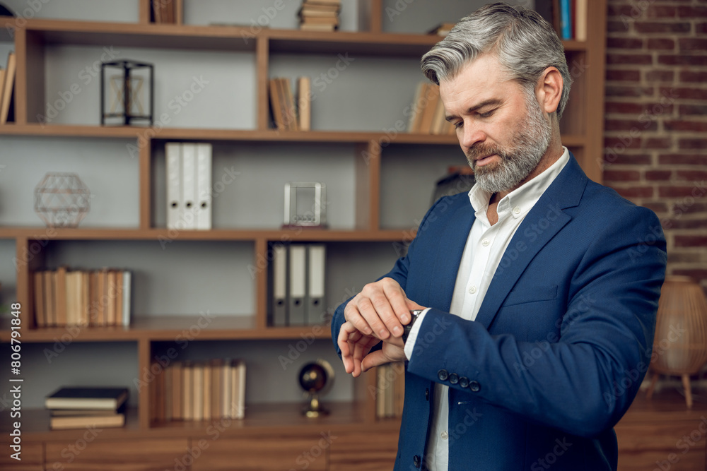 Portrait of happy male psychologist waiting for client on therapy session looking at watch Portrait of happy male psychologist waiting for client on therapy session looking at watch