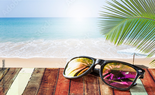 Design sunglasses on old wooden table over tropical beach background, it's summer time, welcome summer, outdoor day light