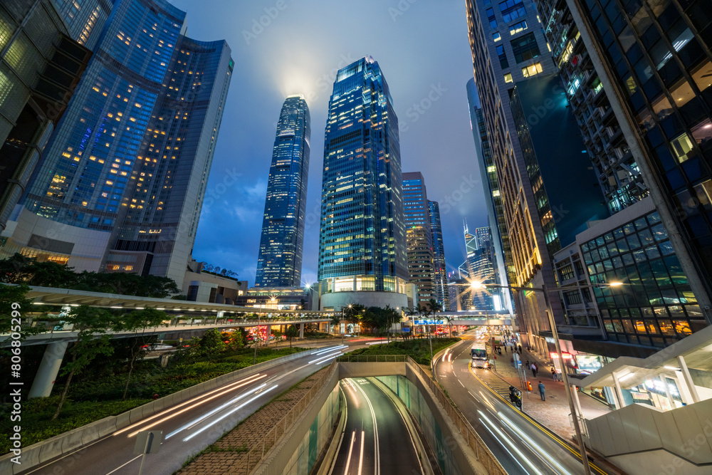 Skyscraper buildings and traffic on road with blurred cars light trails at night, Hong Kong, China