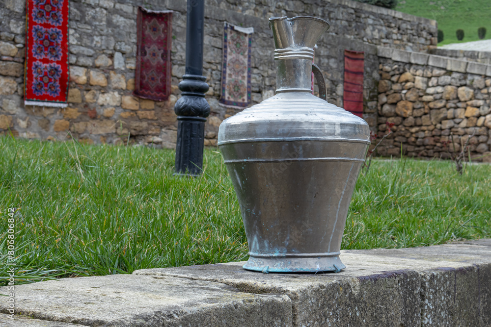 Antique metal vessels for water and wine. A copper jug in an ancient fortress. Antique handmade jugs made in the distant past. Traditional jugs of the Caucasus. Jugs for carrying water by women.