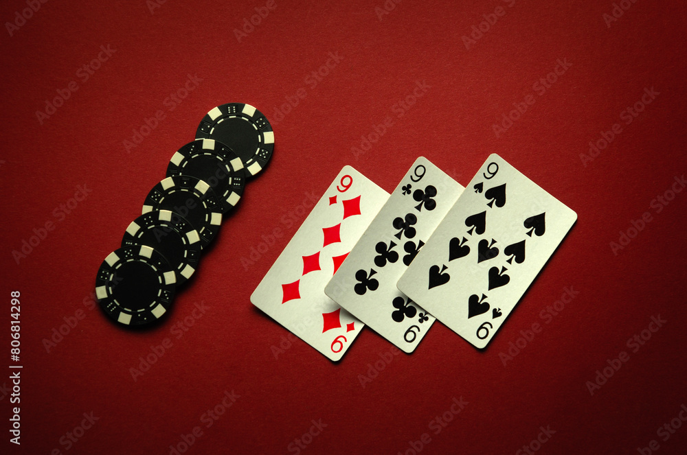 Big luck in a card game of poker with a winning combination of three of a kind or set. Playing cards and chips are laid out in a club on a red table Big luck in a card game of poker with a winning combination of three of a kind or set. Playing cards and chips are laid out in a club on a red table