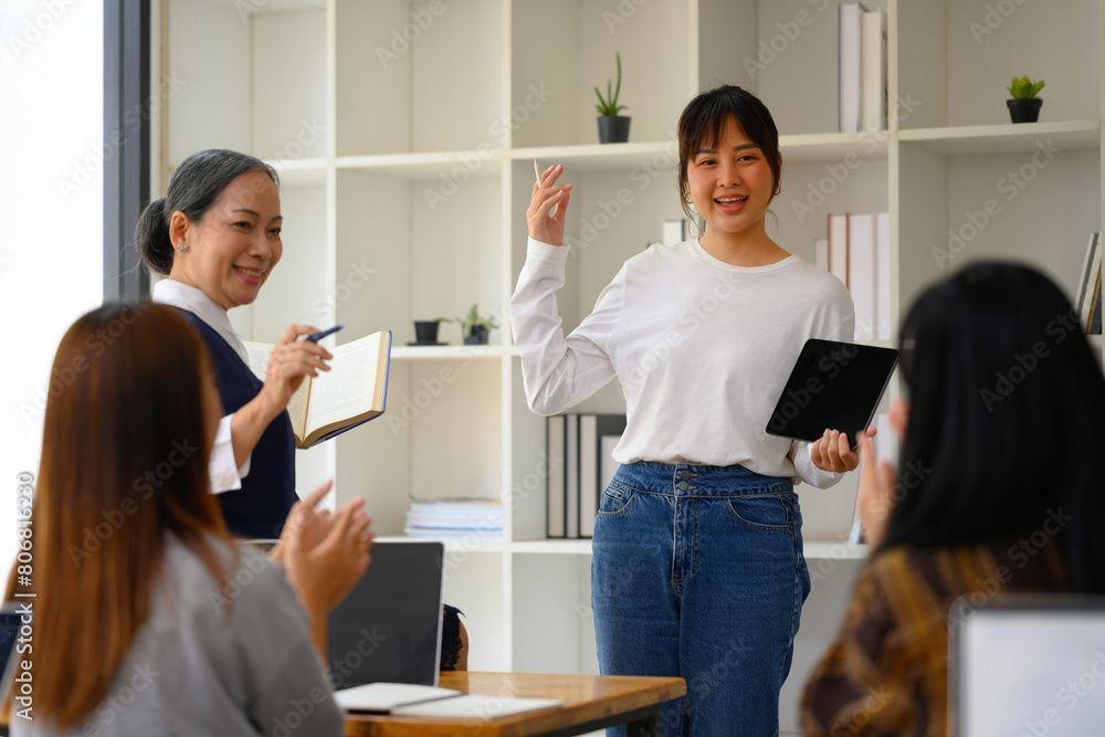 Asian female student with digital tablet giving a presentation in front of classmates Asian female student with digital tablet giving a presentation in front of classmates