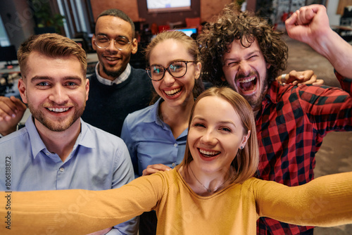 A diverse group of business professionals take a break from their tasks in a modern startup office to capture a creative selfie, showcasing teamwork and a vibrant workplace culture © .shock