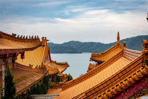 Toits de temple d'architecture chinoise, aux briques oranges, faisant face à un lac et un ciel bleus 